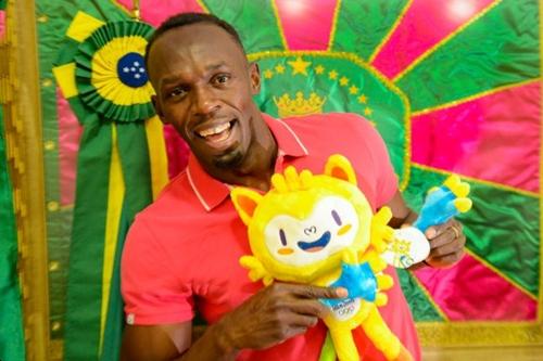 Bolt brinca com Vinicius, o mascote Olímpico, tendo ao fundo a bandeira da Mangueira / Foto: Rio 2016 / Alex Ferro